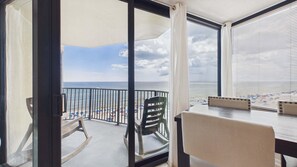 Un balcon avec vue sur la plage, une table et une chaise.