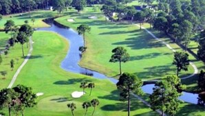 Un parcours de golf avec des bunkers de sable, des obstacles d’eau et des arbres.