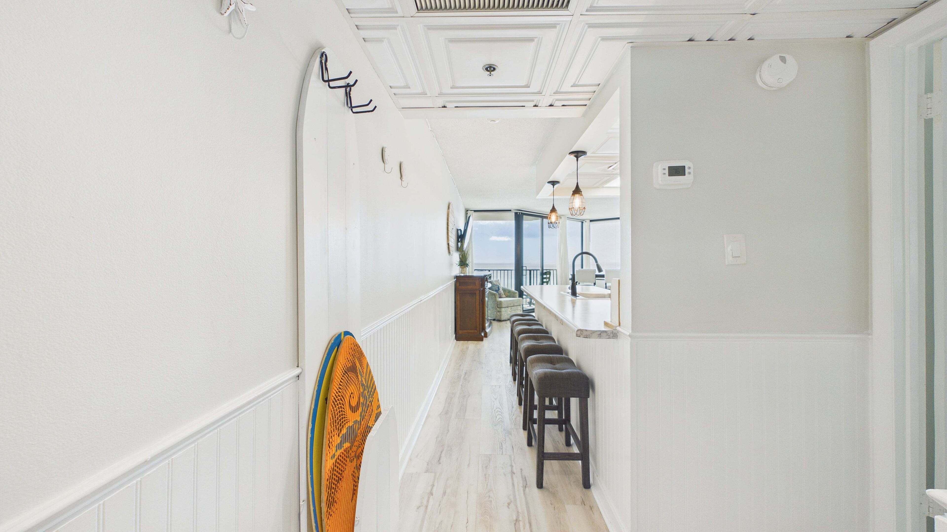 A hallway with a kitchen area, a dining bar, and a view to the outside.