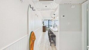 Un couloir donnant sur un espace cuisine, un bar-repas et offrant une vue sur l’extérieur.