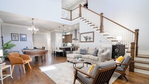 Un salón amplio con escaleras, piso de madera y una zona de comedor.