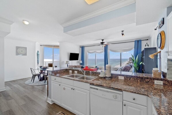 A spacious kitchen with a granite countertop, white cabinetry, and a view of the ocean. - Sea Esta 1900–Gulf Views 2BR–Sleeps 6 (Panama City Beach)