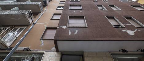 Un edificio de varios pisos con fachada marrón, múltiples ventanas y un escaparate visible con el nombre
