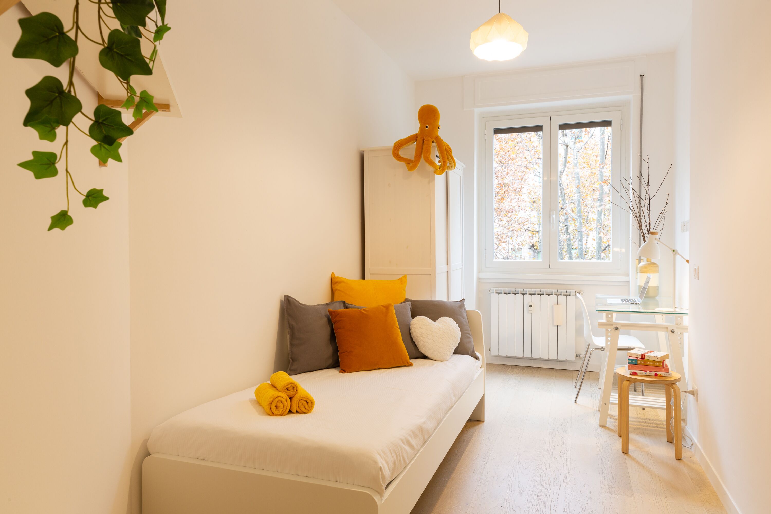 Camera da letto moderna con un divano bianco, un tavolino in vetro e vista sull'esterno.