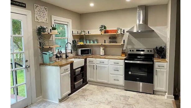 A modern kitchen with white cabinets, a stainless steel oven, a microwave, and a sink. - Renovated 2-bedroom home near Columbus Library (Columbus)