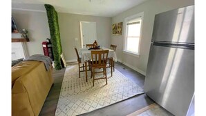 A dining area with a table set for four, a large refrigerator, and a sofa in the foreground. - Renovated 2-bedroom home near Columbus Library (Columbus)