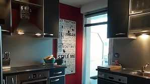A modern kitchen with stainless steel appliances, wooden flooring, and a red accent wall. - Very nice apartment downtown, Parc Olympe de Gouges ( with garage) (Annemasse)