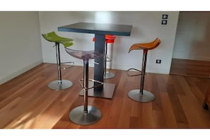Un coin repas avec une table et trois tabourets de bar.