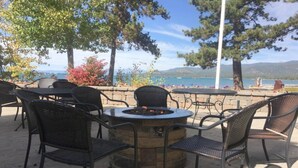 Un espace extérieur aménagé avec un foyer, des fauteuils en osier et une vue sur le lac.