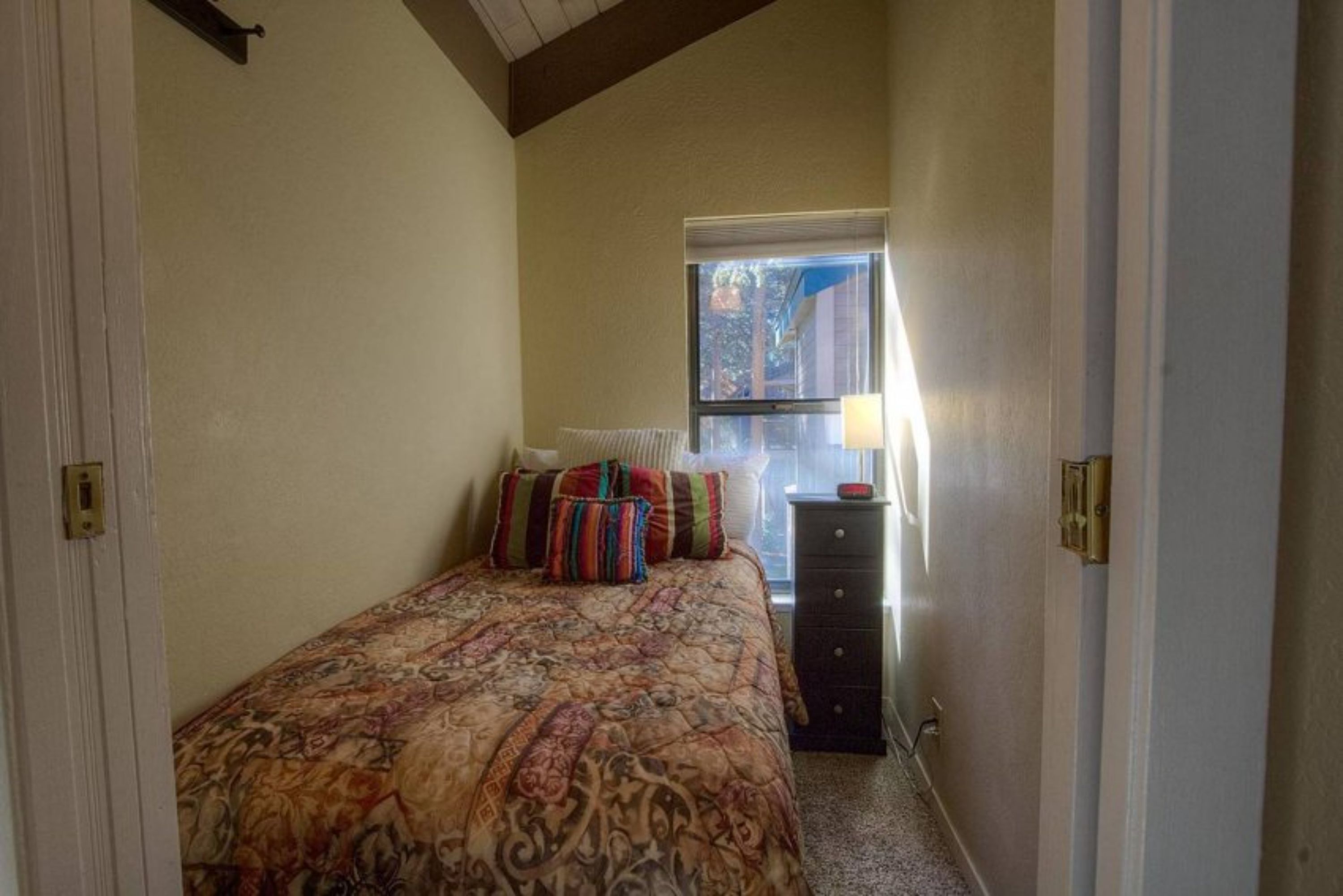 Un dormitorio con cama, cómoda, ventana y radiador.