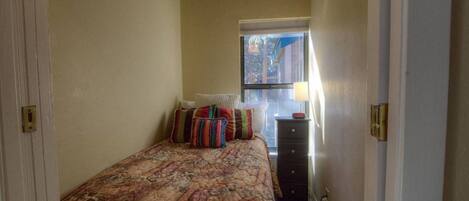 Un dormitorio con cama, cómoda, ventana y radiador.