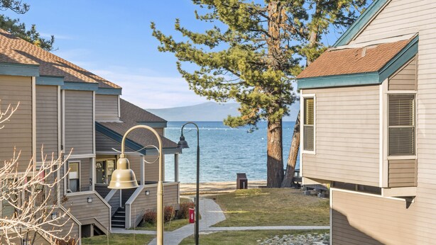 Un quartier résidentiel situé sur la côte, avec des maisons, une cloche et une vue dégagée sur l’eau.