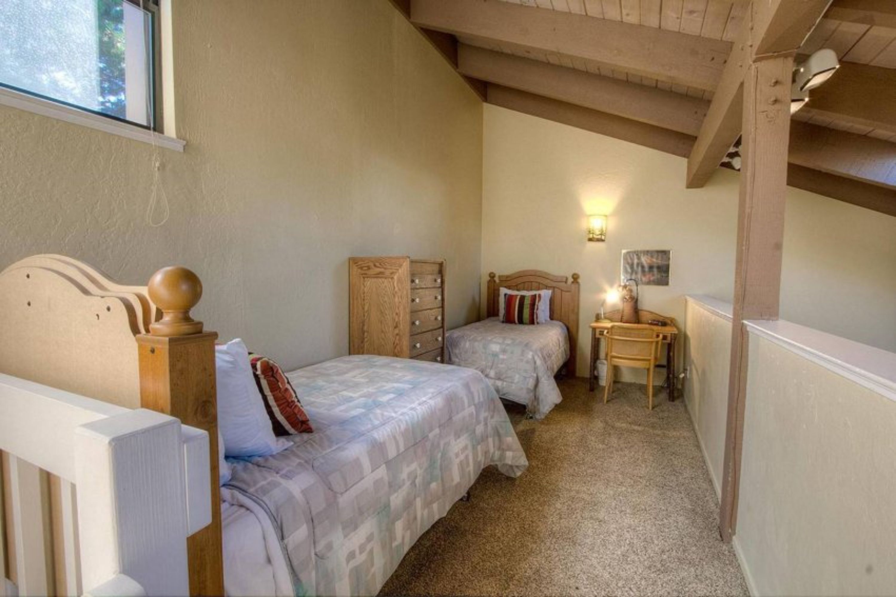 Un dormitorio con dos camas, un aparador de madera, un escritorio y una silla.