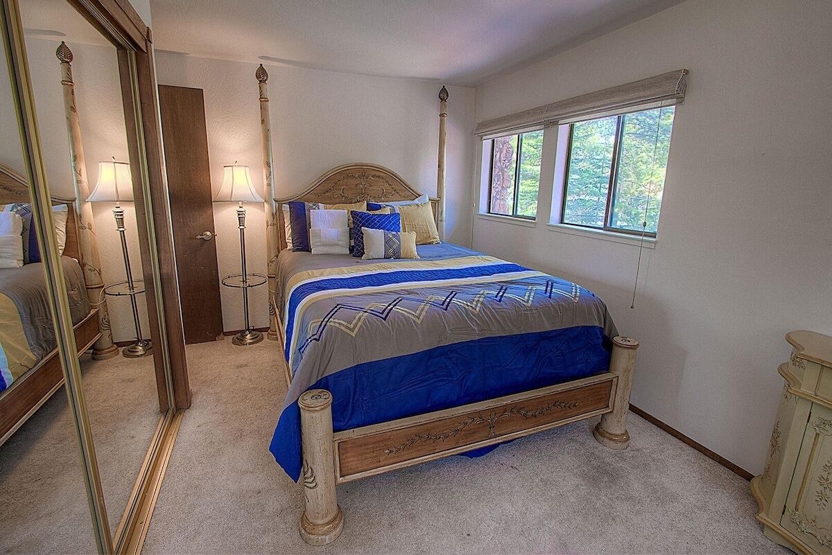 Um quarto com uma cama grande, duas luminárias de cabeceira, um espelho e uma janela.