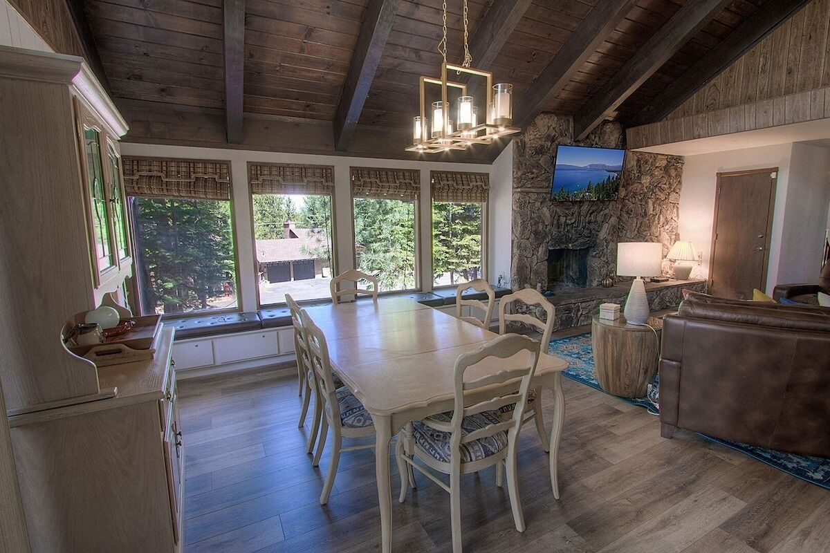 Un coin repas avec une table et des chaises en bois, une cheminée en pierre et un téléviseur fixé au mur.