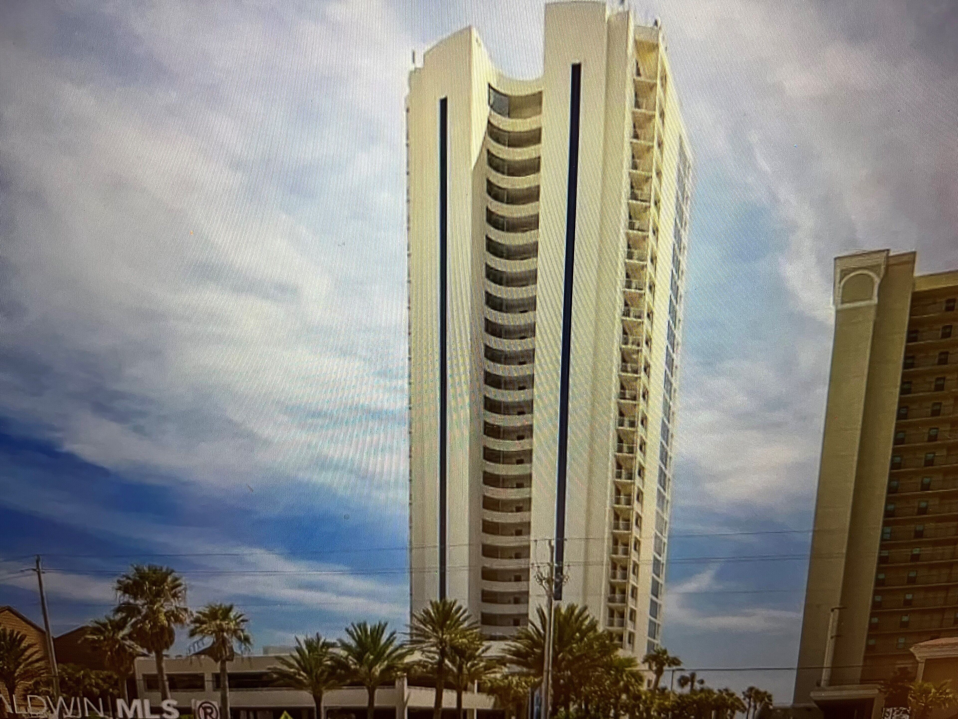 A tall, modern building with a curved facade and multiple balconies.