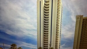 A tall, modern building with a curved facade and multiple balconies.