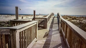 A wooden boardwalk leading to a beach with a clear sky.