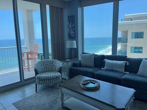 A modern living room with a large balcony, a sofa, a chair, a coffee table, and a view of the ocean. -  Just steps from the beach! The most incredible sunrise to Sunset views! (Gulf Shores)