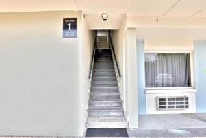Una escalera conduce a la entrada de un edificio, con un cartel que indica Edificio 1, 110-118, 201-223.