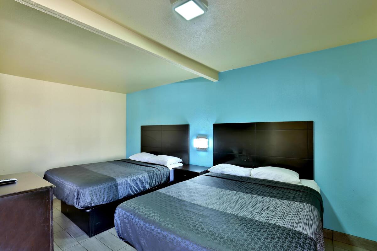 Ein Hotelzimmer mit zwei Betten, einem Schreibtisch und einem Nachttisch.