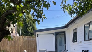 A backyard with a patio area, a white house, and a wooden fence. - Little White House on Ecclestone close to city centre and Tamar Valley Wineries! (Riverside)