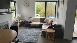A modern living room with a sectional sofa, a round coffee table, a dining table, and a fireplace. - Little White House on Ecclestone close to city centre and Tamar Valley Wineries! (Riverside)