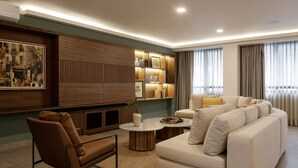 Ein modernes Wohnzimmer mit einer Eckcouch, einem braunen Sessel, einem Couchtisch und einem an der Wand befestigten Fernseher.