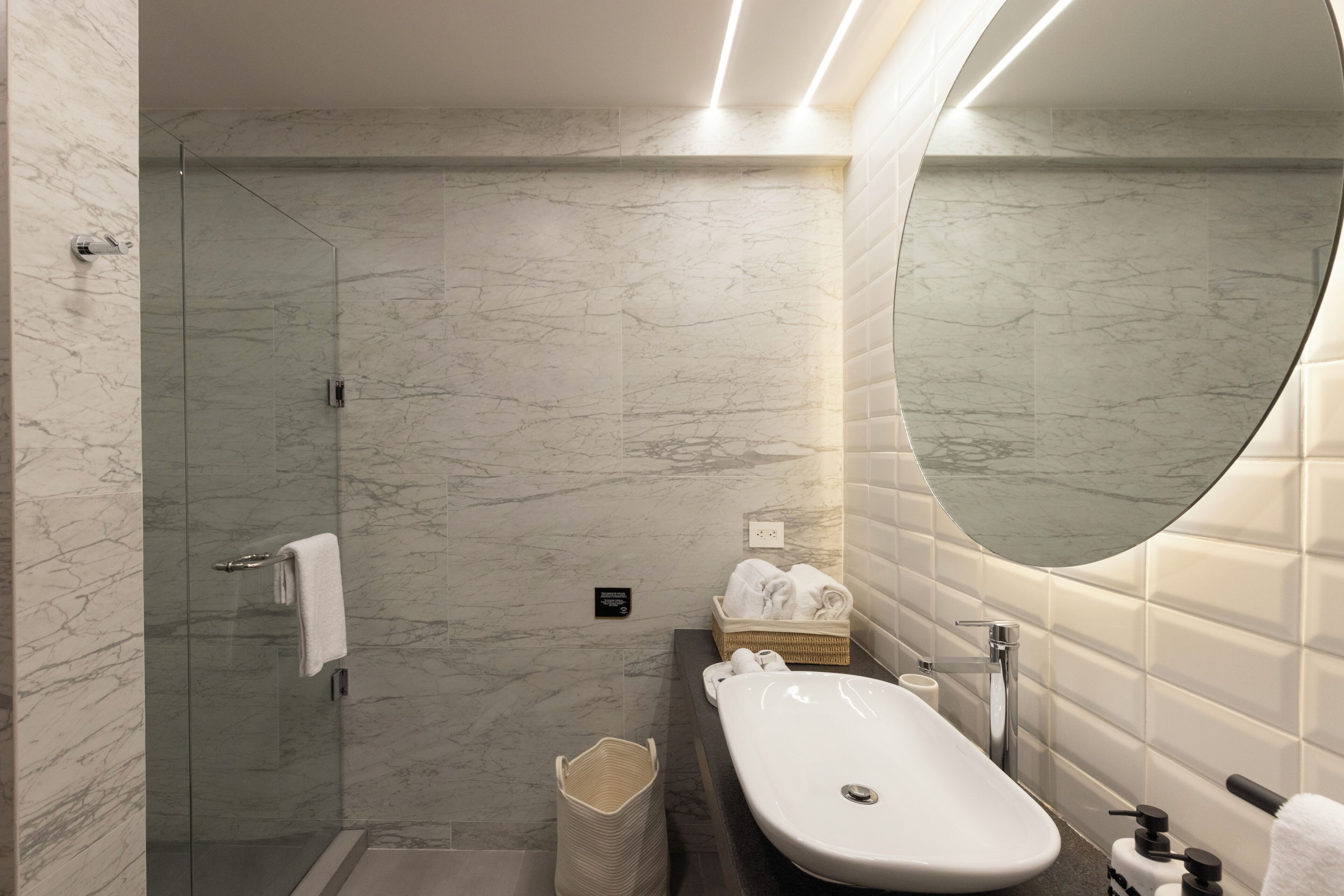 A modern bathroom with a glass-enclosed shower, a freestanding bathtub, and a large mirror.