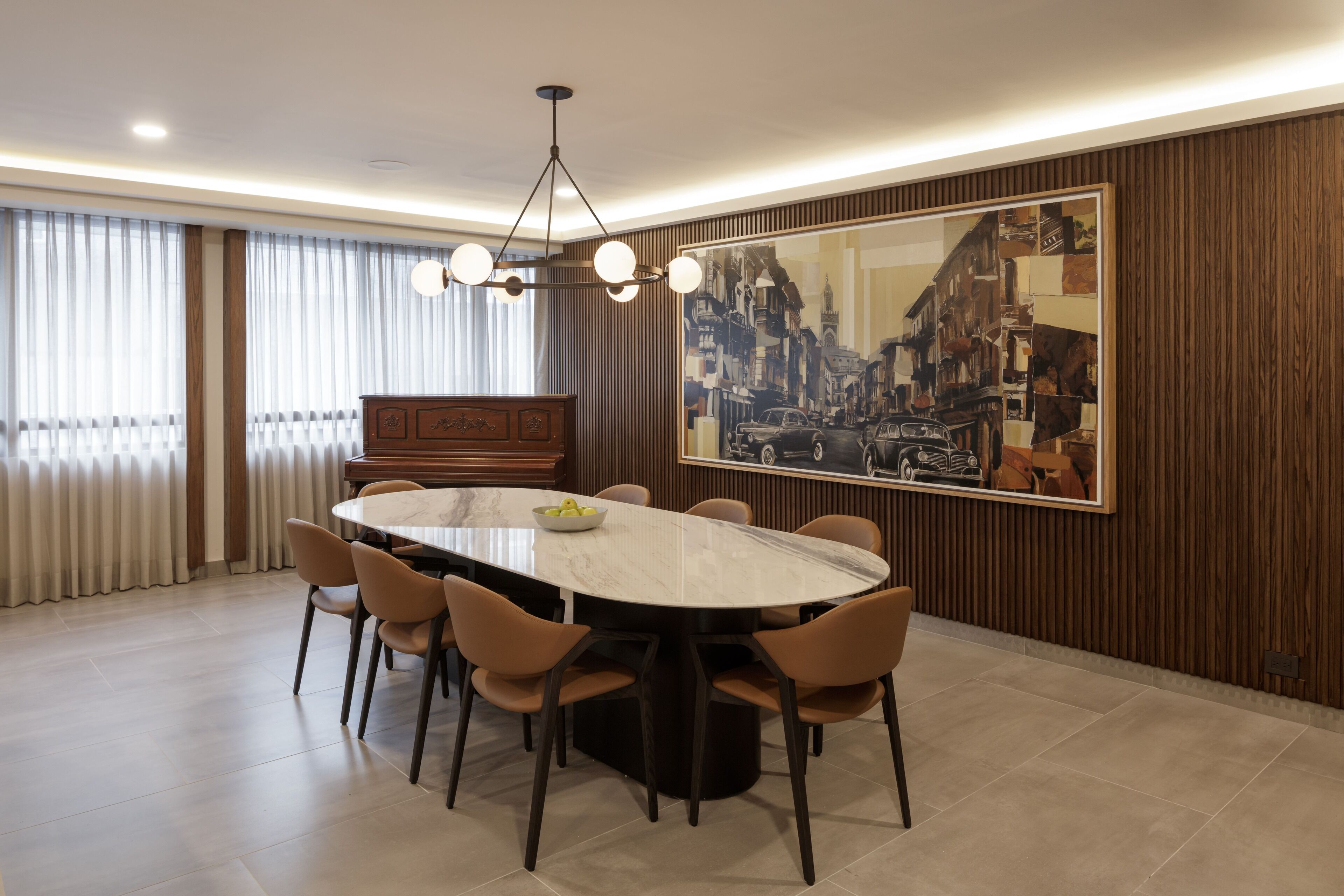 A dining room with a round table, six chairs, a chandelier, and a large cityscape painting on the wall.