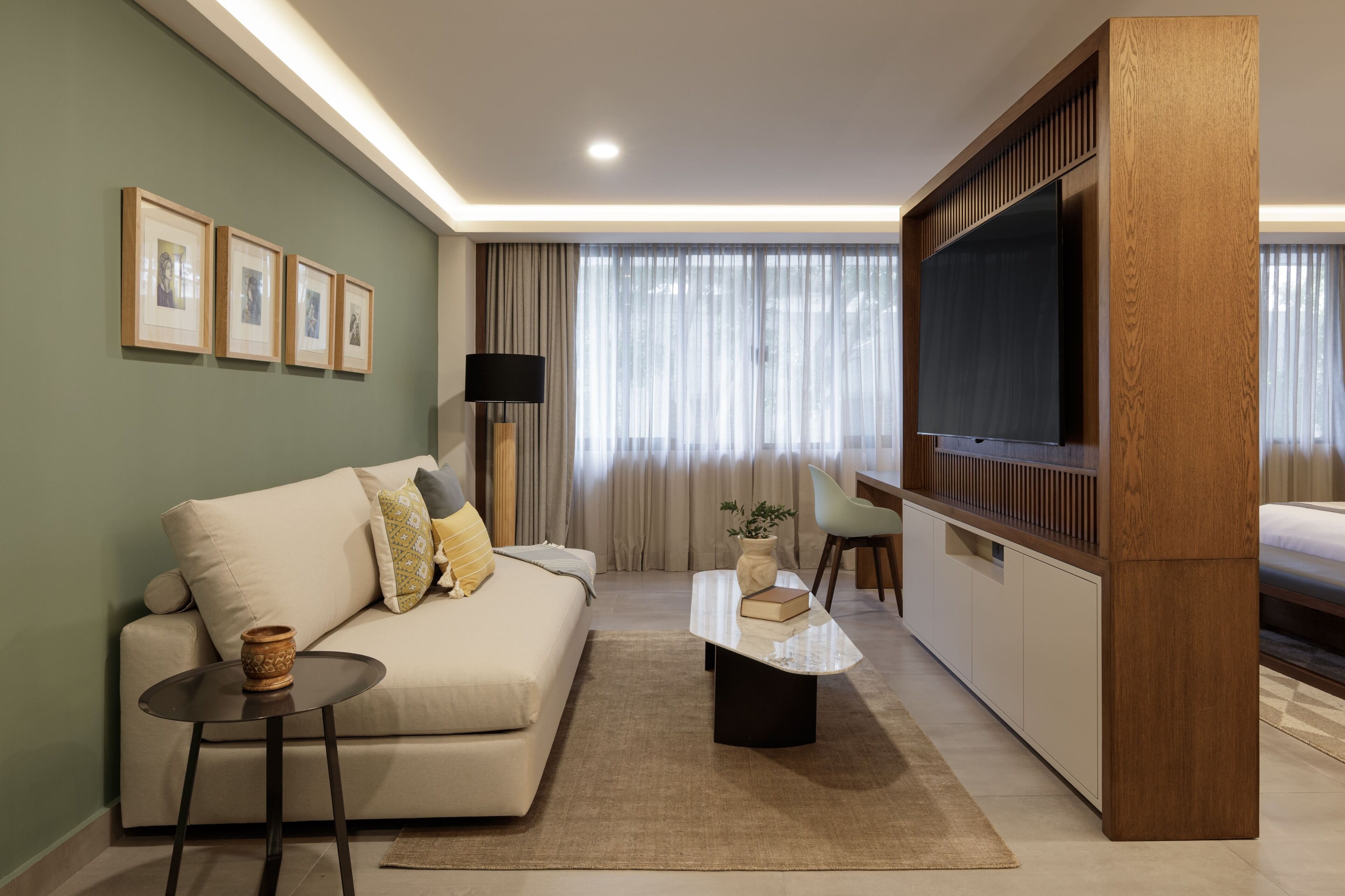 A modern living room with a sofa, a coffee table, a TV, and framed pictures on the wall.