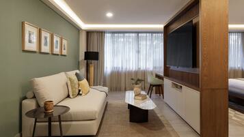 Una sala de estar moderna con un sofá, una mesa de centro, un televisor y cuadros en la pared.