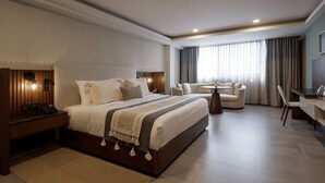 Ein modernes Hotelzimmer mit einem großen Bett, einem Schreibtisch, einer Couch und einem Esstisch.