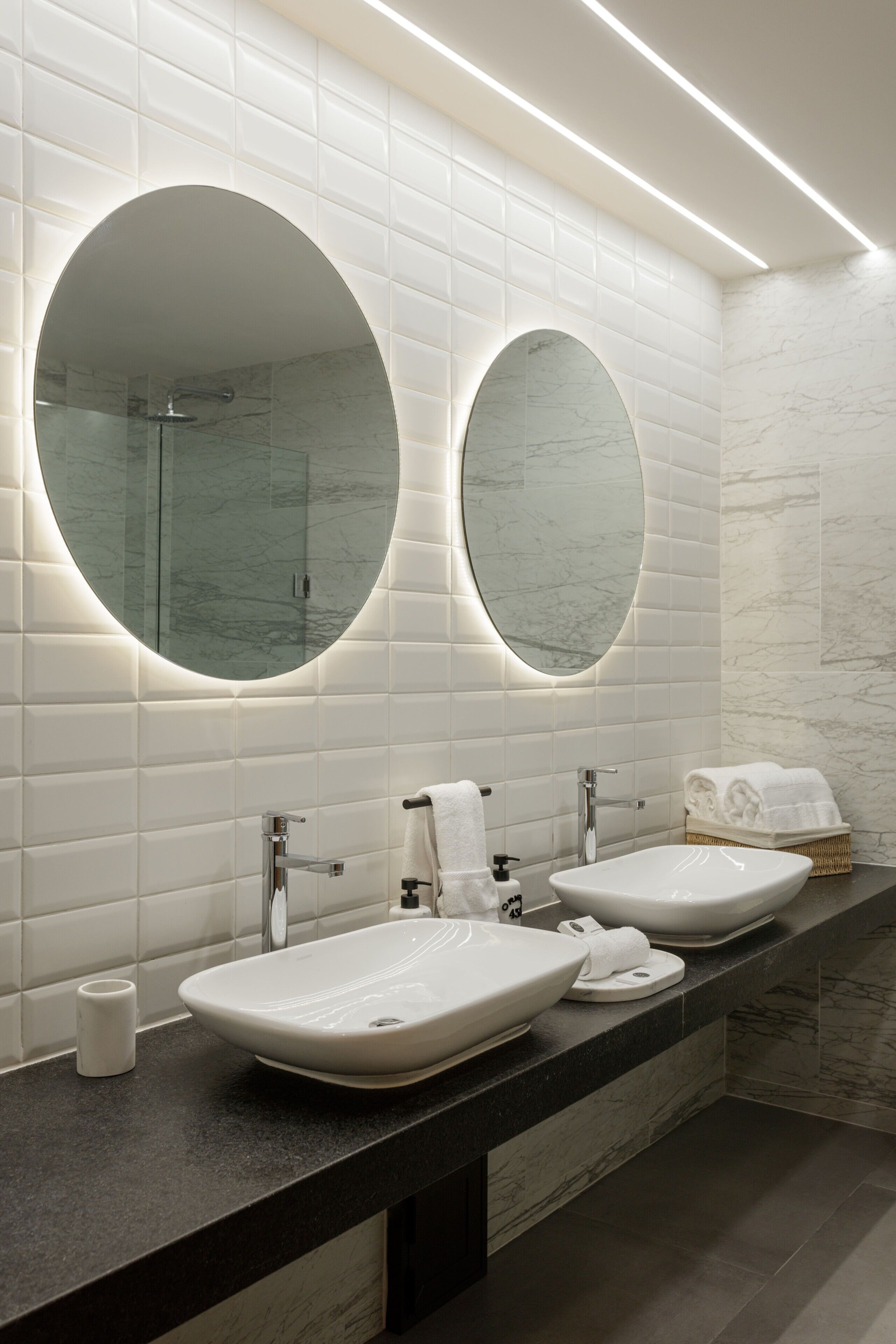 A modern bathroom with two sinks, a large mirror, and a glass shower enclosure.