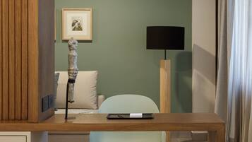 Une pièce moderne avec un bureau en bois, une chaise vert clair, un canapé blanc, une lampe sur pied et un tableau encadré au mur.