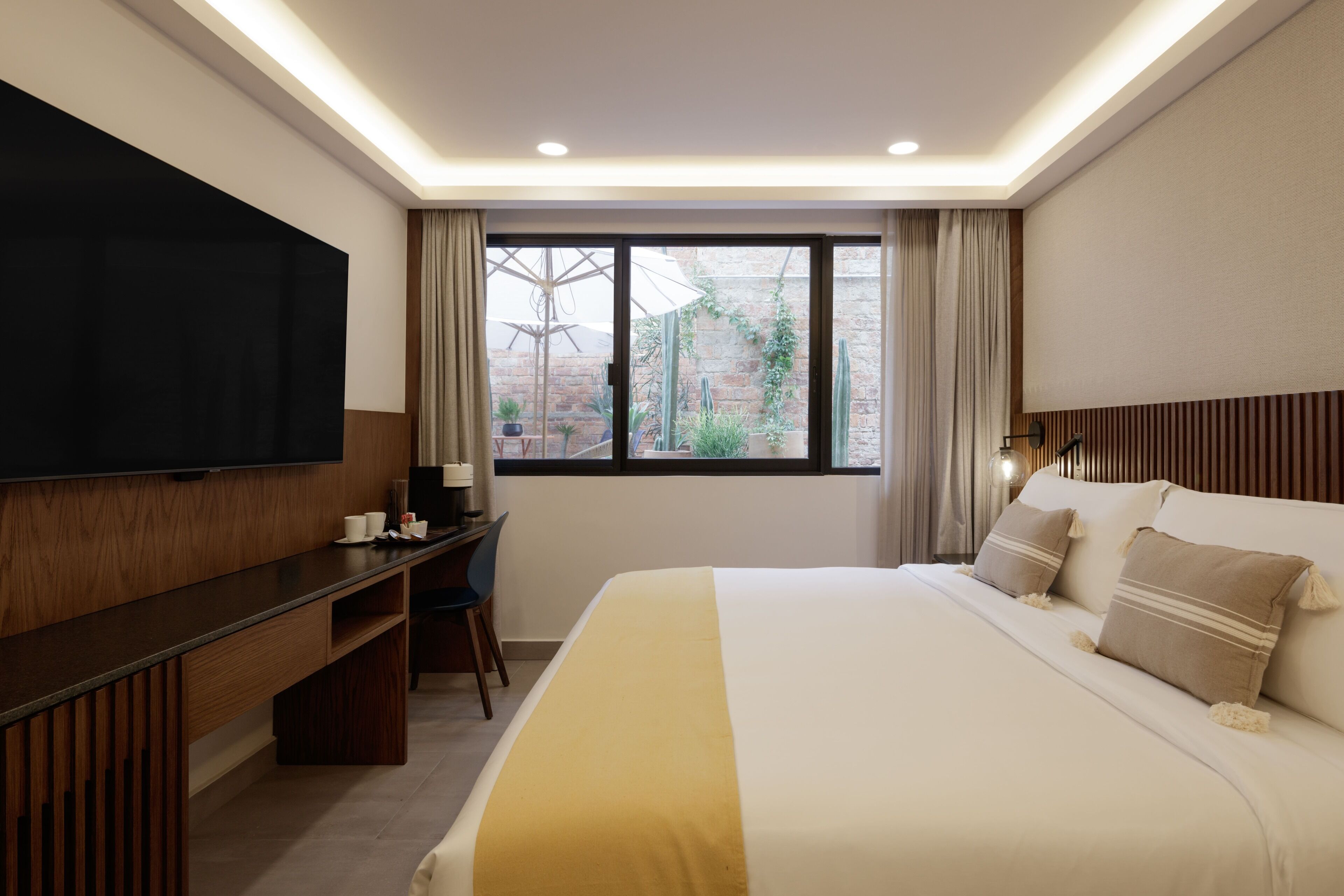 Habitación de hotel con una cama grande, televisor de pantalla plana, escritorio y ventana con cortinas.