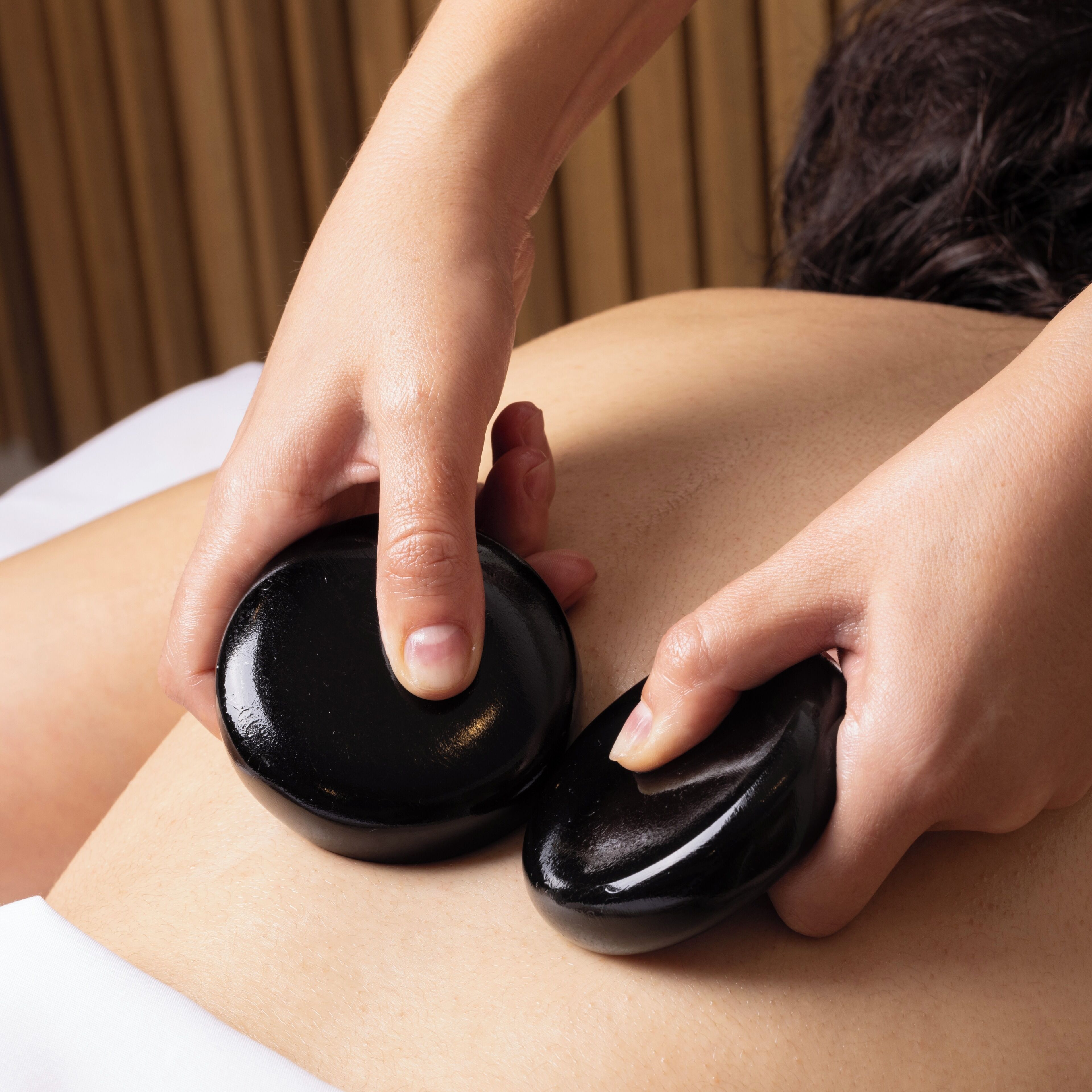 A close-up of hands using a massage tool on a person's back.