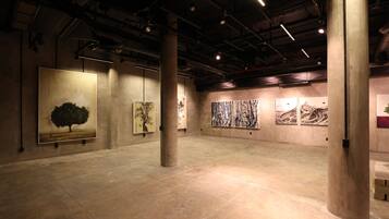 Une galerie d’art où les murs sont ornés de grandes peintures et où l’espace au sol est vaste.