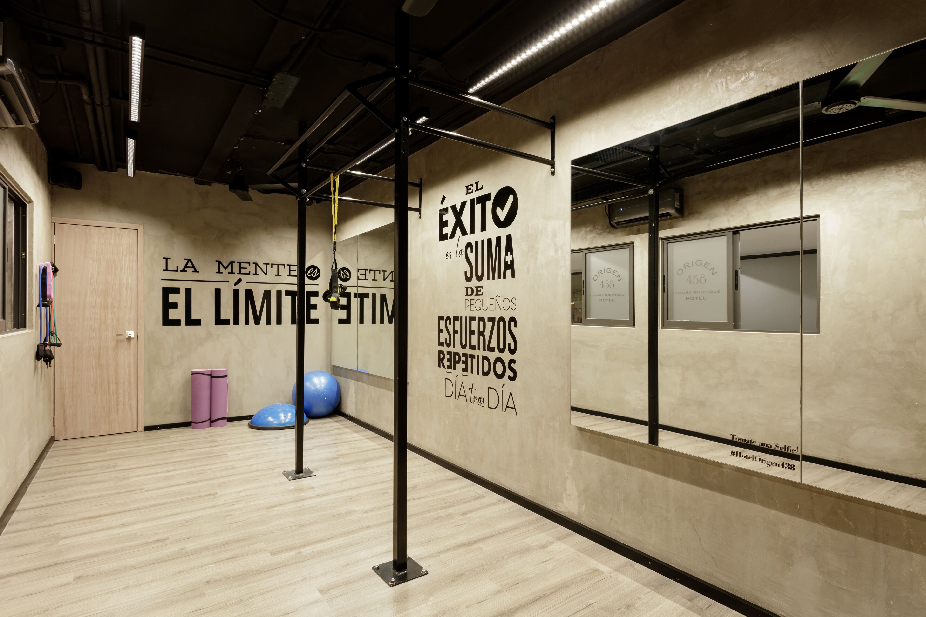 Ein Fitnessstudio mit Trainingsgeräten, motivierenden Wandtexten und Holzboden.