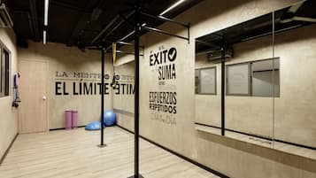 Ein Fitnessstudio mit Trainingsgeräten, motivierenden Wandtexten und Holzboden.