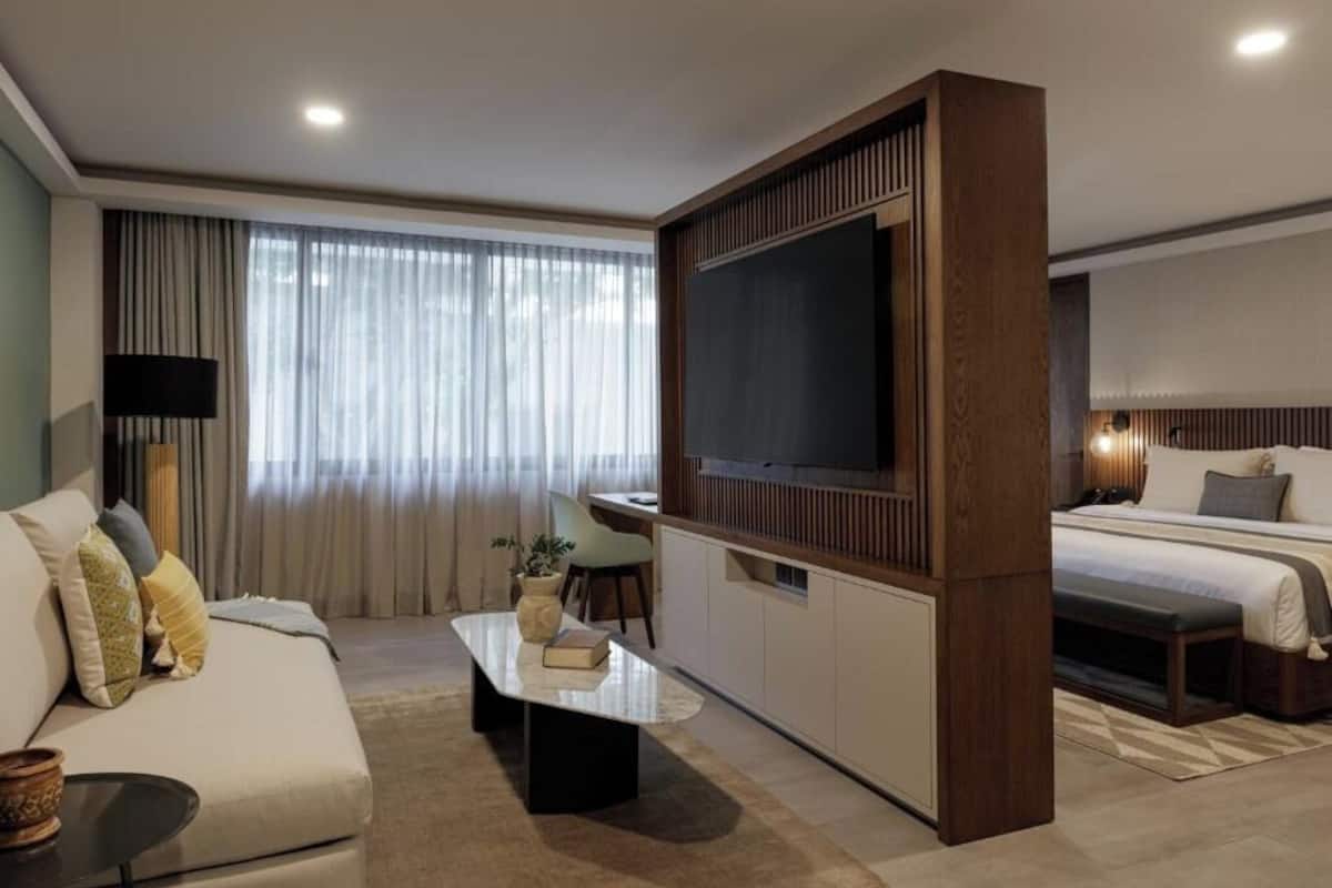 Une chambre d’hôtel moderne dotée d’un grand téléviseur à écran plat, d’un canapé, d’un coin repas et d’un lit.