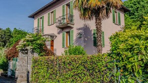 A two-story building with green shutters, a balcony, and a stone gate. - Villa Gard by Wonderful Italy (Bellagio)