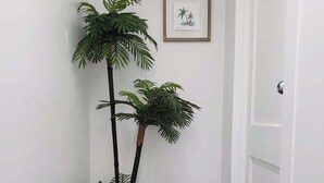 Un pasillo con un felpudo, un cuadro en la pared y dos macetas.