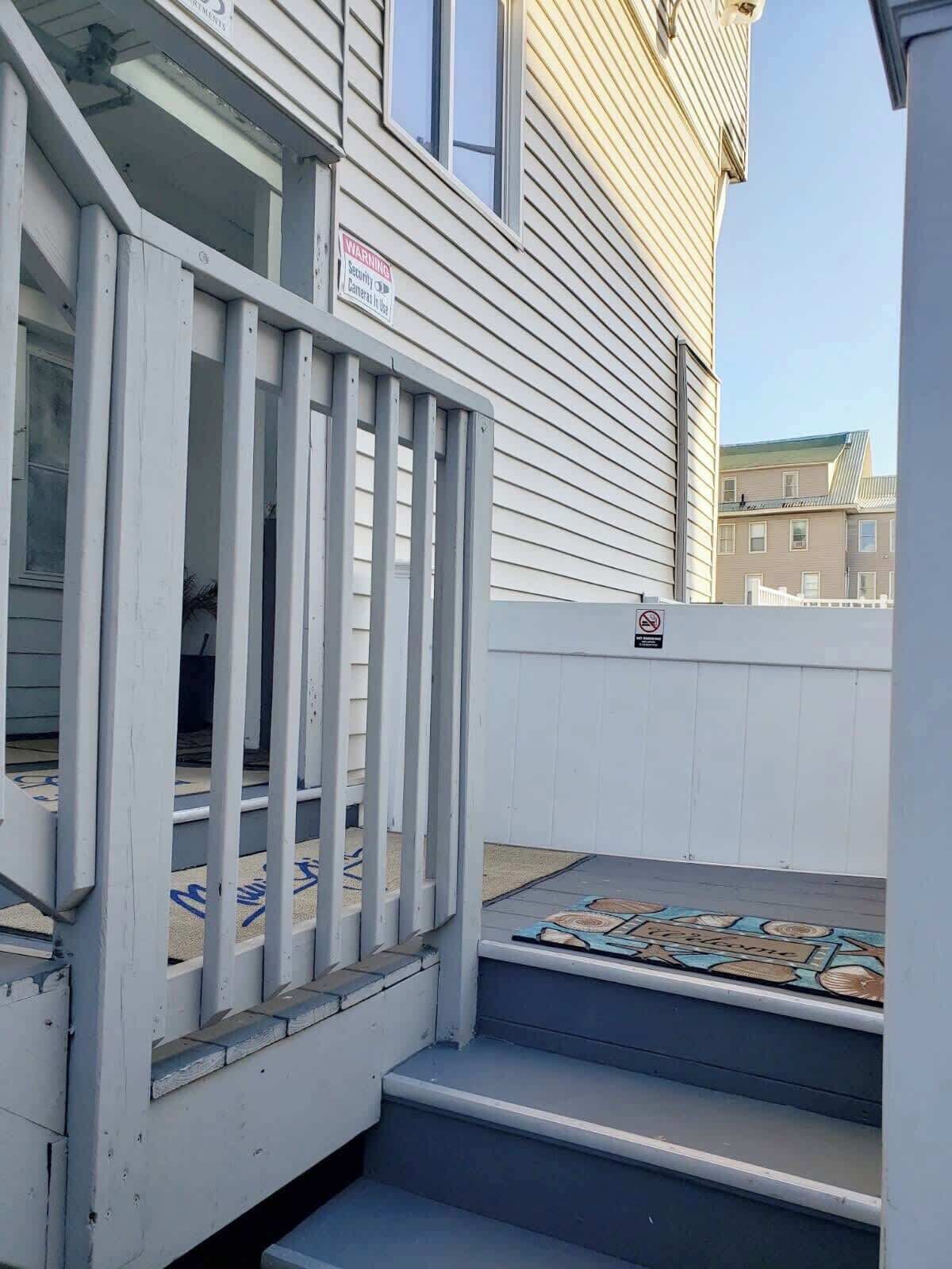 A set of outdoor stairs leading to a building with a security camera warning sign.
