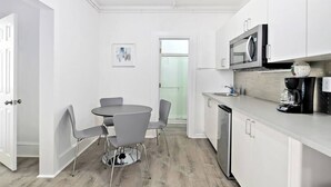 A modern kitchen with white cabinets, a microwave, and a coffee maker. - Modern Beachfront Suite 301 (Ocean City)
