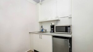 Eine kompakte Küchenzeile mit Mikrowelle, Kaffeemaschine, Spüle und Geschirrspüler.