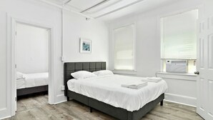 Ein Schlafzimmer mit einem Bett, einem Fenster mit Jalousien und einer Tür.