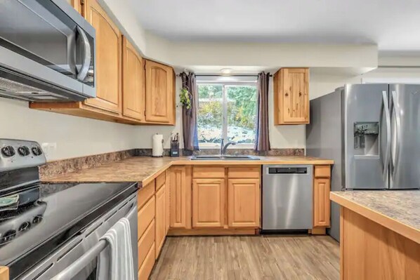 Enjoy cooking in this kitchen with a stove, stainless steel appliances, and cabinetry, plus a dishwasher and a window with a view.