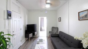 Un salon avec un canapé, une table basse, un téléviseur et une plante.