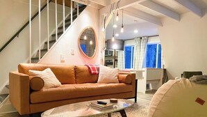 Ein modernes Wohnzimmer mit einem braunen Ledersofa, einem runden Couchtisch und einem Sitzsack.